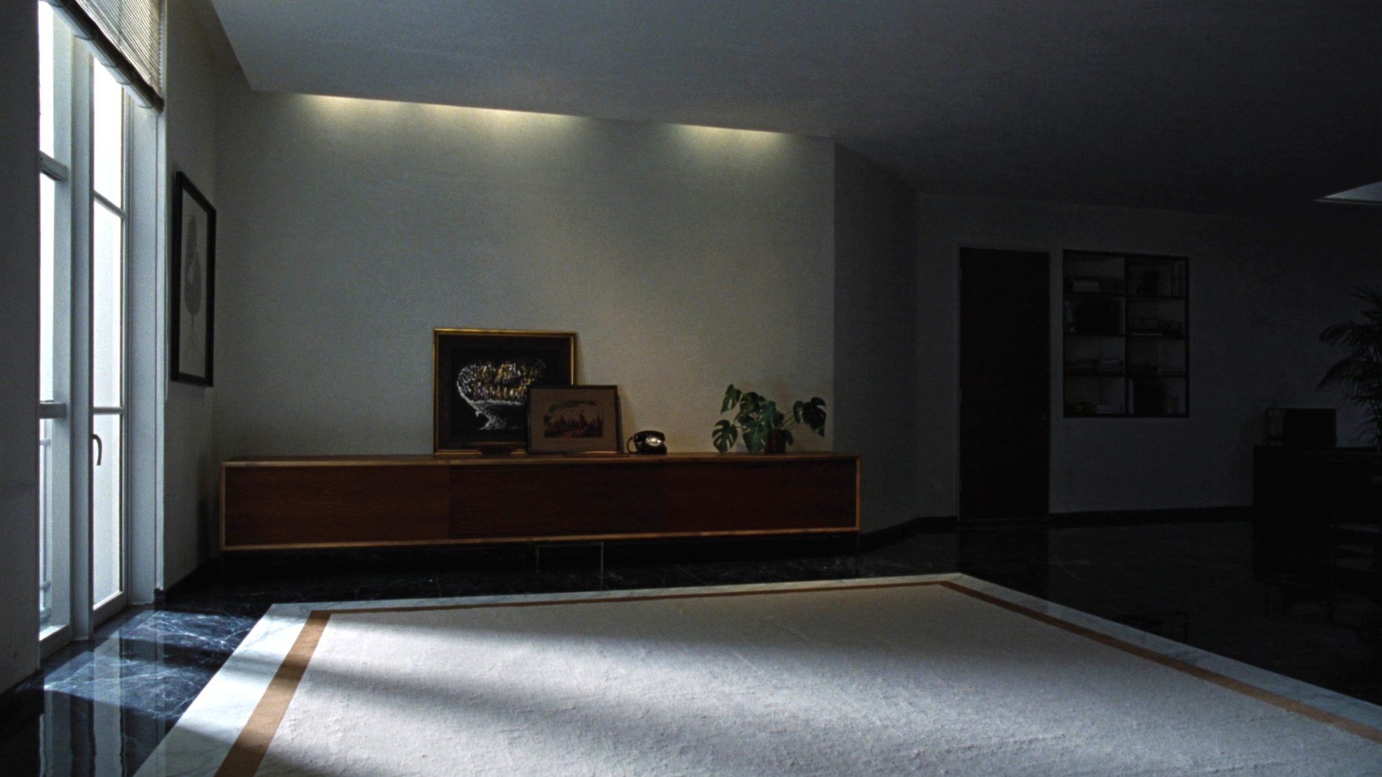 Low walnut credenza against a bone plaster wall in an executive office